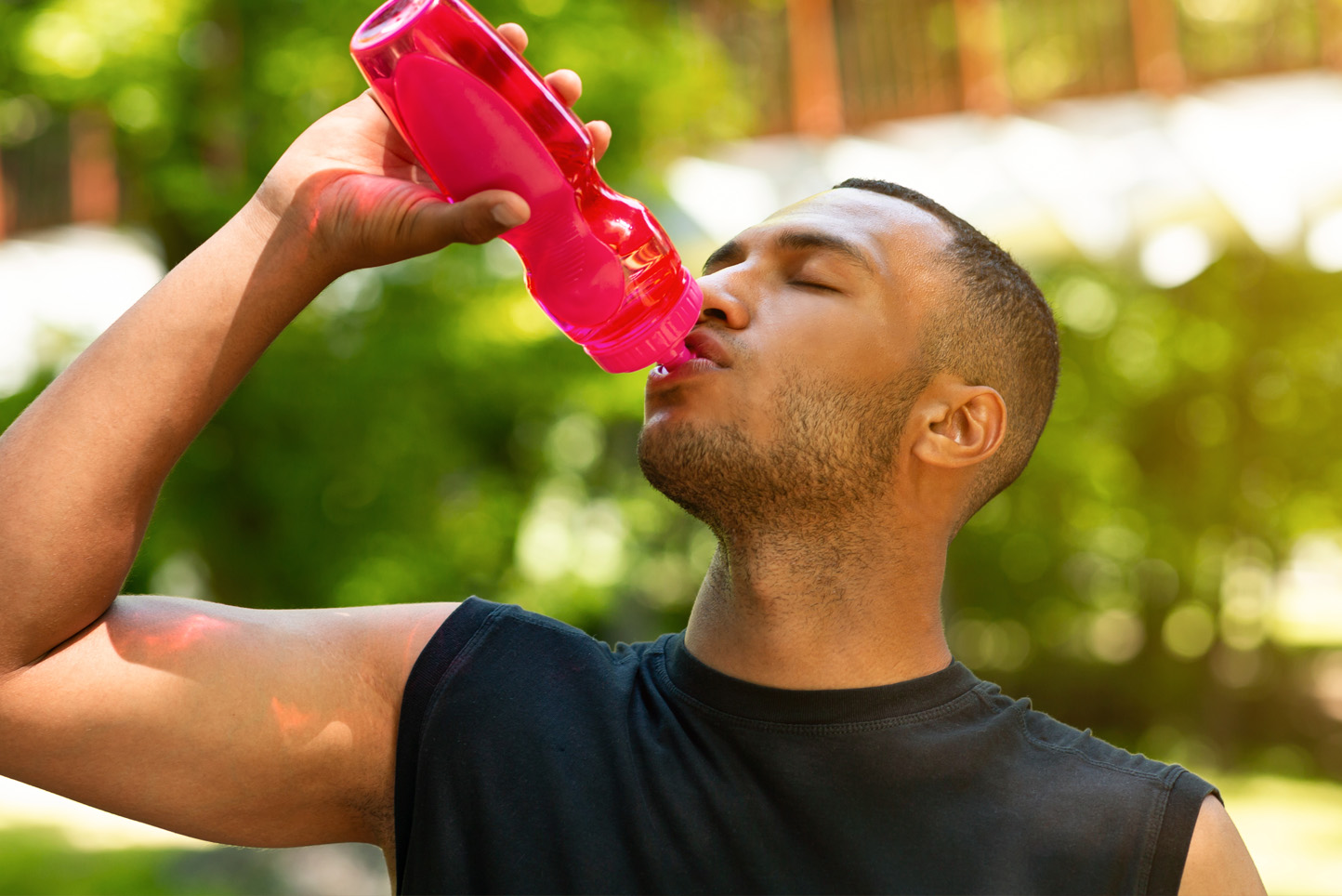 Athlete drinking out of water bottle after outdoor exercise