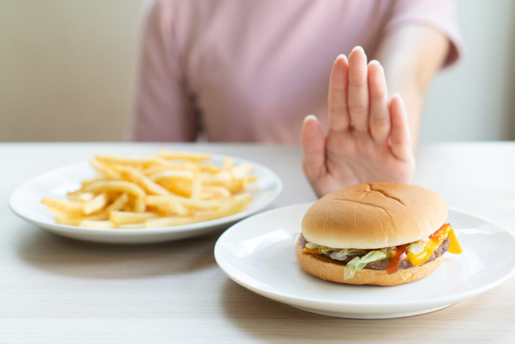 Hand pushing away a hamburger and fries
