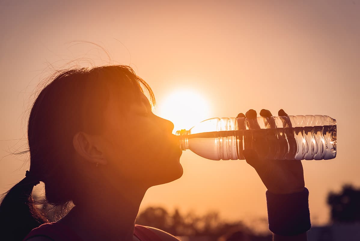 Woman staying hydrated while outside in the heat.