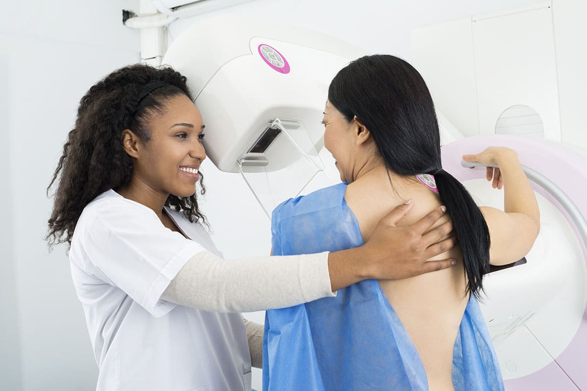 Provider assisting woman with a mammogram.
