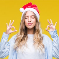 Woman with Santa hat on and making a peaceful gesture.