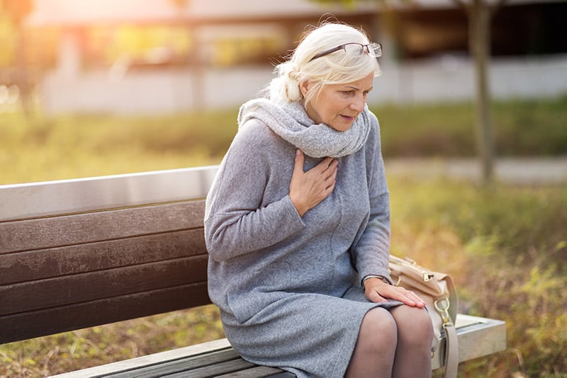 Women on park bench holding heart.