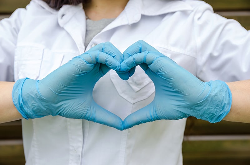 Hands in medical gloves forming a heart symbol.